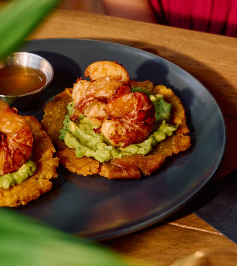 Shrimp tostones with avocado on a black plate at Arca Roatan